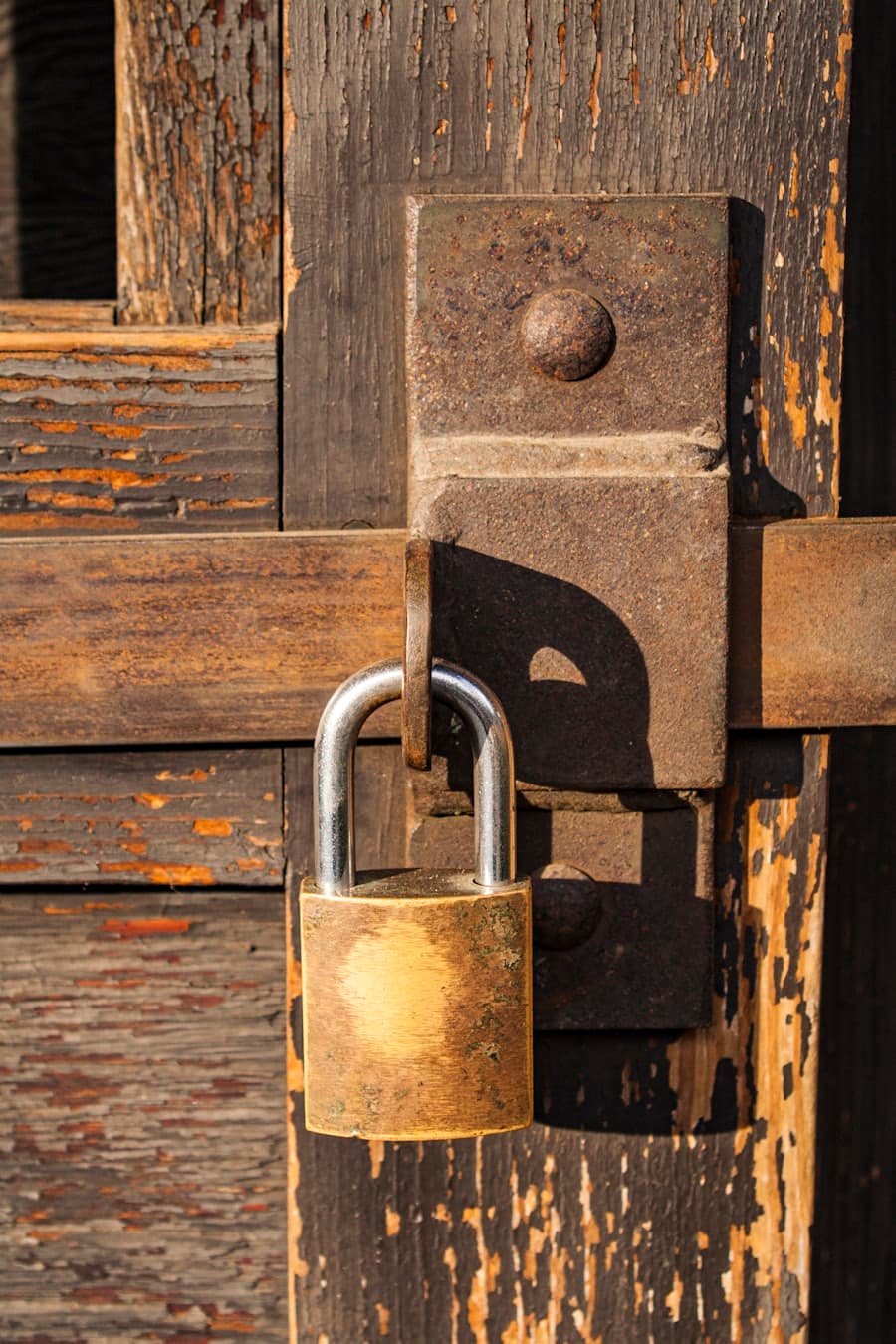 A brass padlock securing a weathered wooden door