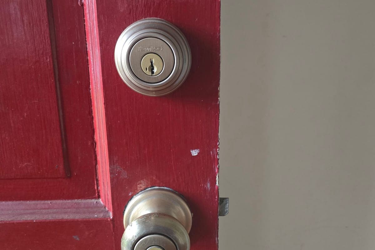 A Kwikset deadbolt and knob on a red front door